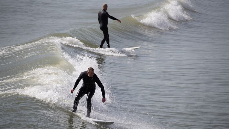 Une personne surfe une vague dans la mer au large de la plage de Bournemouth dans le Dorset.  Date de la photo: mardi 30 mars 2021. Les températures dans certaines parties du Royaume-Uni devraient être nettement plus chaudes cette semaine, car les familles et les amis sont réunis et les activités sportives sont autorisées à reprendre en Angleterre.