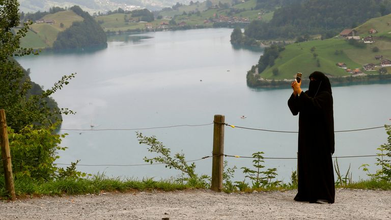 A woman wearing a niqab takes a picture from a lookout above lake Lungenersee at the Bruenigpass mountain pass road, Switzerland 