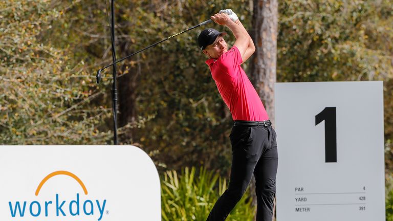 Carlos Ortiz plays his shot from the first tee dressed in Red and Black in support of Tiger Woods 