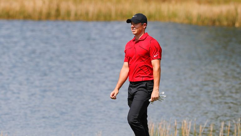 Rory McIlroy walks to the second green wearing red and black