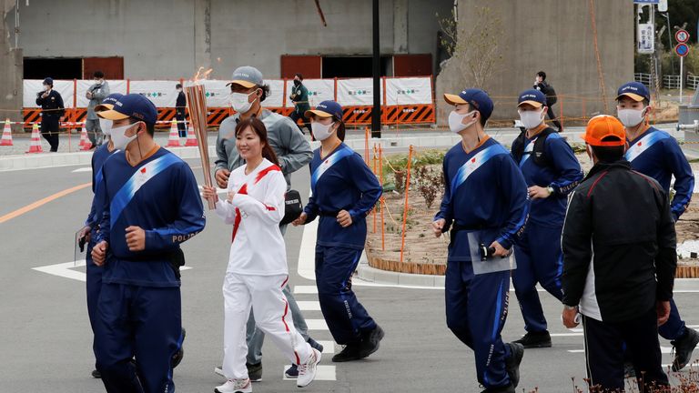 A torch bearer runs past an abandoned building in Fukushima