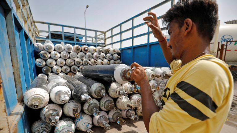 A worker loads empty oxygen cylinders onto a supply van to be transported to a filling station, at a COVID-19 hospital, amidst the spread of the coronavirus disease (COVID-19) in Ahmedabad, India, April 22, 2021. REUTERS/Amit Dave