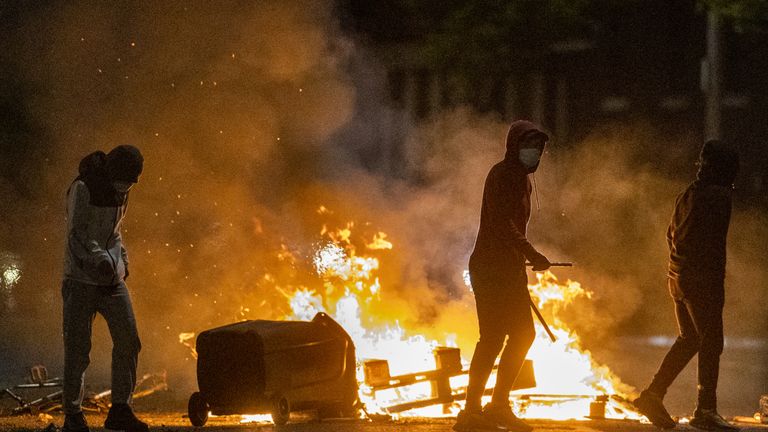 مردم در کنار آتش در خیابانی در بلفاست ایستاده اند