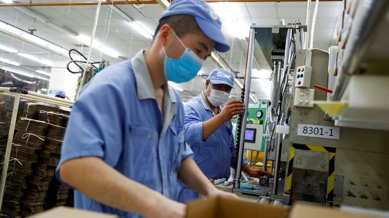 Employees wearing masks work at a factory of the component maker SMC during a government organised tour of its facility following the outbreak of the coronavirus disease (COVID-19), in Beijing, China May 13, 2020.