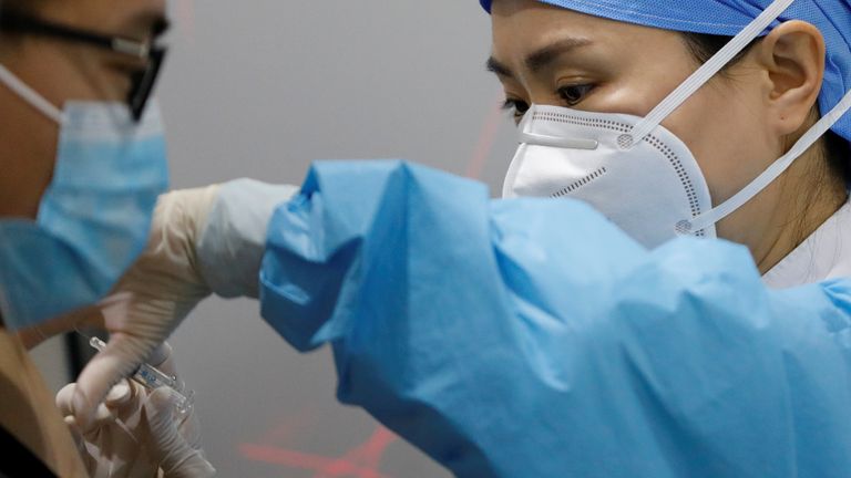 A medical worker prepares to administer a COVID-19 vaccine to a man at a vaccination site in Beijing, China