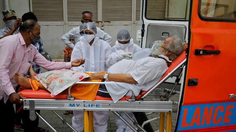 A patient wearing an oxygen mask is wheeled into a hospital in Ahmedabad
