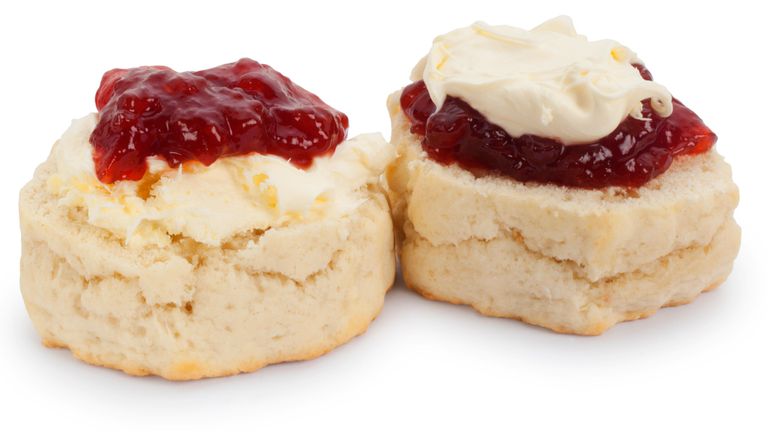 Studio shot of homemade scones, clotted cream and strawberry jam. It is traditional in the county of Cornwall, UK to have the cream on top of the jam. In Devon, UK, the jam is on top.