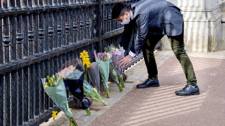 A member of the public leaves flowers outside Buckingham Palace, London, following the announcement of the death of the Duke of Edinburgh at the age of 99. Picture date: Friday April 9, 2021.