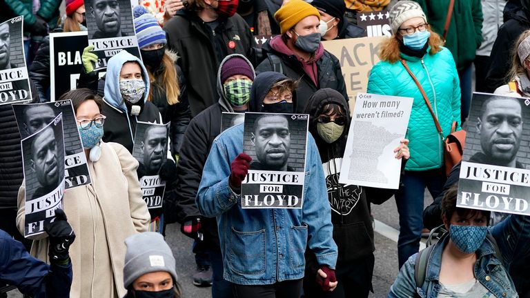 People hold signs as they march near the Hennepin County Government Center during a rally in Minneapolis on Monday, April 19, 2021, after the murder trial against former Minneapolis police officer Derek Chauvin advanced to jury deliberations. (AP Photo/Julio Cortez)