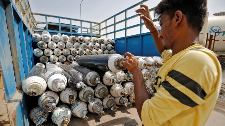 Un travailleur charge des bouteilles d'oxygène vides sur une camionnette à Ahmedabad