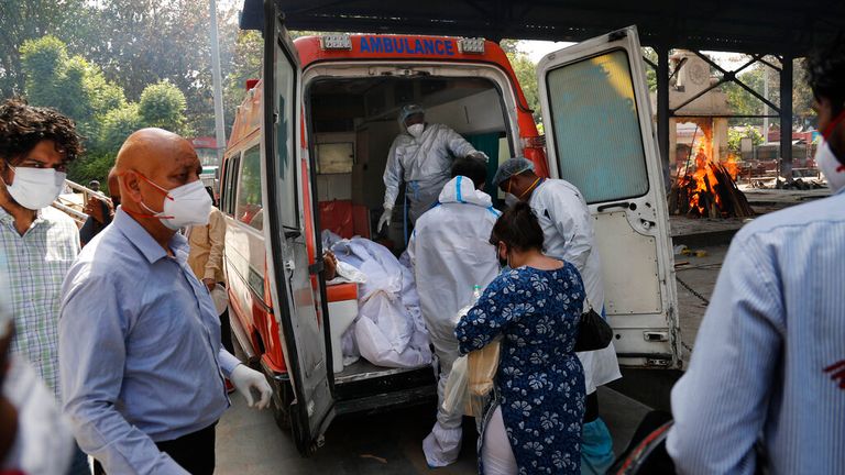 Workers prepare to remove the bodies of six COVID victims in New Delhi on Monday