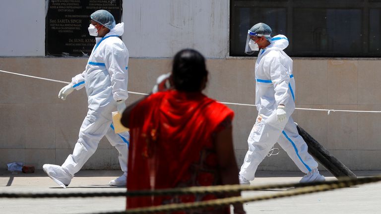 A health worker wearing personal protective equipment (PPE) carries an oxygen cylinder into the casualty ward at Guru Teg Bahadur Hospital, in New Delhi, India, April 24, 2021. REUTERS/Adnan Abidi