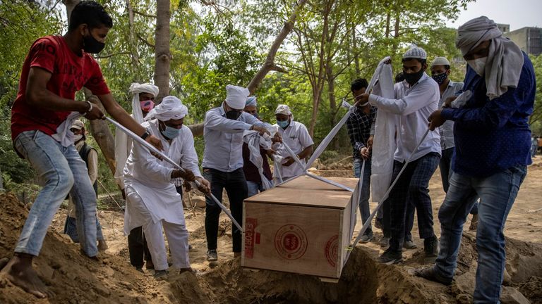 People bury the body of a man, who died from coronavirus disease at a graveyard in New Delhi