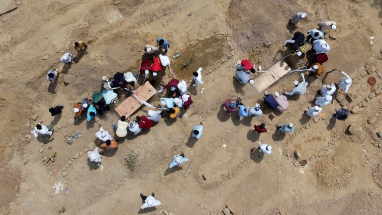 People bury bodies at a graveyard in Delhi. The graveyard has had to turn away bodies as it runs out of space 