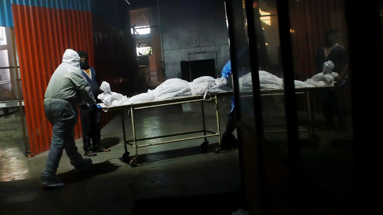 The body of someone who died with coronavirus being pushed into a crematorium in Delhi