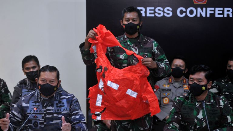 Ein Soldat hält einen Fluchtanzug in der Hand, der vermutlich von der versunkenen indonesischen Marine stammt