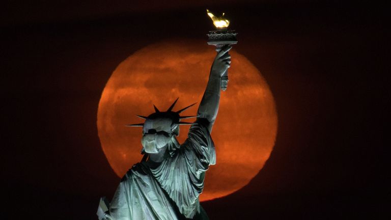 La pleine lune, connue sous le nom de "Super lune rose" s'élève derrière la Statue de la Liberté à New York, États-Unis, le 27 avril 2021. REUTERS / Bjoern Kils / New York Media Boat PAS DE REVENTE.  PAS D'ARCHIVES