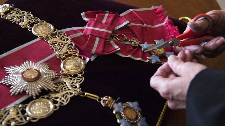 Diane Hatcher, a seamstress at Cleave Court Jewellers, sews medals and decorations conferred on the duke