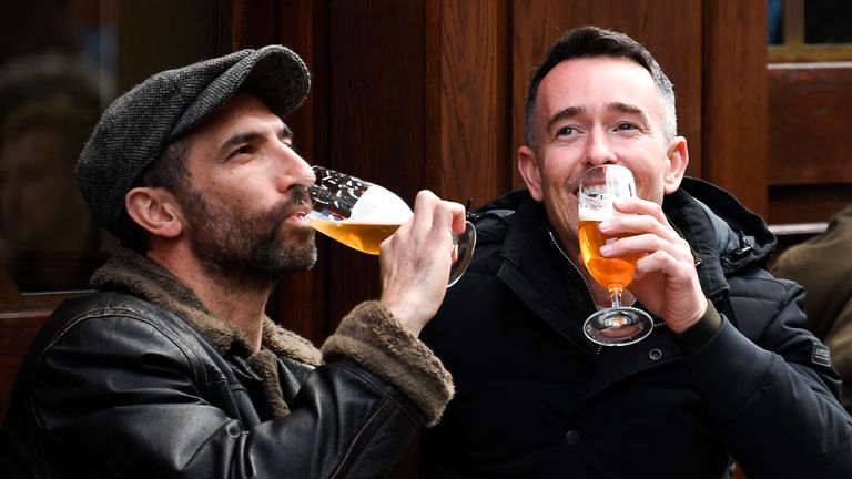 People drink beer at tables setup outside a pub in Soho, in London, on the day some of England's third coronavirus lockdown restrictions were eased by the British government, Monday, April 12, 2021. People across England flocked to shed shaggy locks and browse for clothes, books and other 