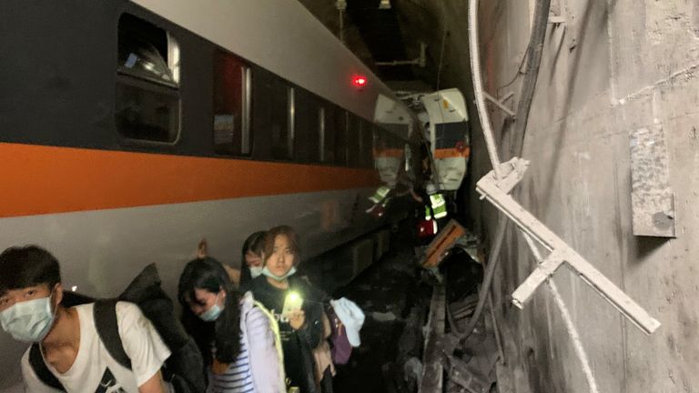 People walk next to a train which derailed in a tunnel north of Hualien, Taiwan April 2, 2021, in this handout image provided by Taiwan&#39;s National Fire Agency. Taiwan&#39;s National Fire Agency/Handout via REUTERS ATTENTION EDITORS - THIS IMAGE WAS PROVIDED BY A THIRD PARTY. NO RESALES. NO ARCHIVES.