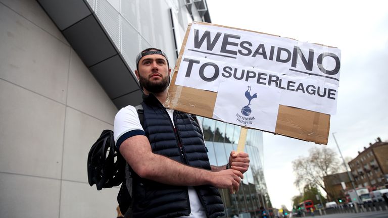 A Spurs fan clutches a placard outside their north London stadium