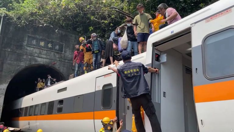 Beberapa penumpang berjalan di sepanjang bagian atas kereta untuk keluar dari terowongan