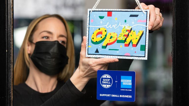 EDITORIAL USE ONLY Manager Louise Hughes from Muse of London displays a "we&#39;re open" sign designed by artist Yukai Du, which has been created as part of the American Express Shop Small campaign and to help welcome people back to our high streets. London.