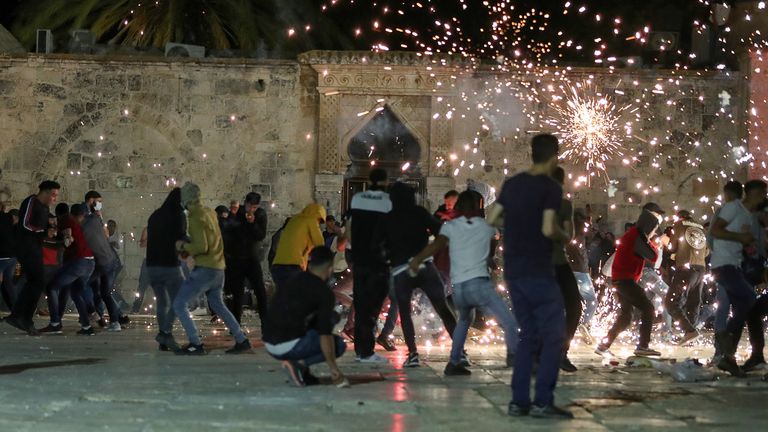 Palestinians react as Israeli police fire stun grenades during clashes at the compound that houses Al-Aqsa Mosque, known to Muslims as Noble Sanctuary and to Jews as Temple Mount