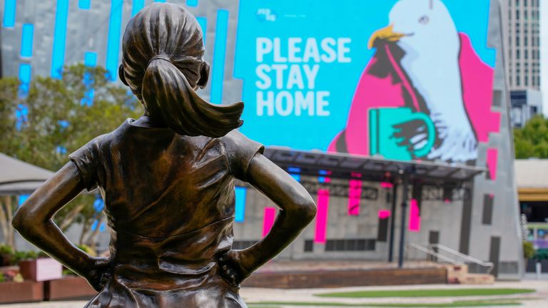 The Fearless Girl Statue looks at a &#34;Please Stay Home&#34; sign in an empty Federation Square in Melbourne, Victoria