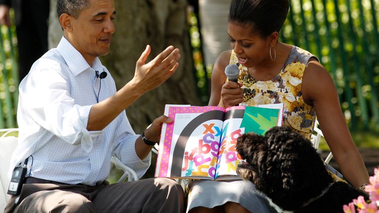 U.S. President Barack Obama reacts to their dog Bo (bottom) as first lady Michelle Obama (R) reads a book titled "Chicka Chicka Boom Boom" to children during the annual Easter Egg Roll, at the White House in Washington April 25, 2011