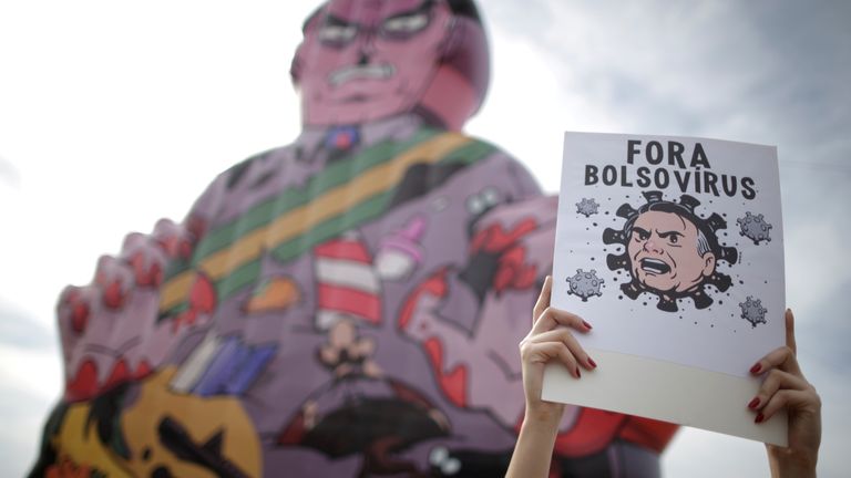 A banner is held up during protests in Brasilia, which reads "Bolsonaro virus out"