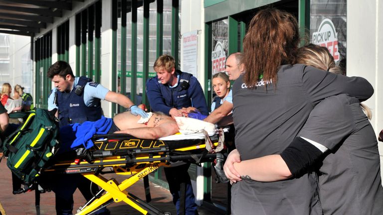 Supermarket staff embrace as police officers take a victim to an ambulance outside a Countdown supermarket in central Dunedin, New Zealand, Monday May 10, 2021. Pic: AP