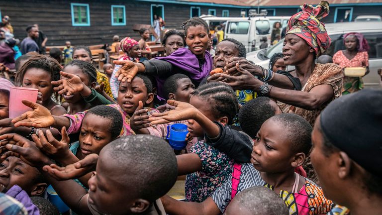 People who fled Goma, Congo gather at a food distribution point Friday, May 28, 2021  in Sake, some 25 kms (16 miles) west of Goma  where they found shelter following an official evacuation order five days after Mount Nyiragongo erupted. (AP Photo/Moses Sawasawa)