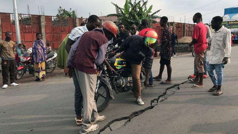 People inspect a crack on the road caused by earth tremors