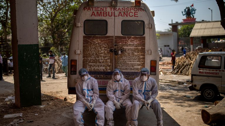 Exhausted workers gets some rest on the back of an ambulance in New Delhi