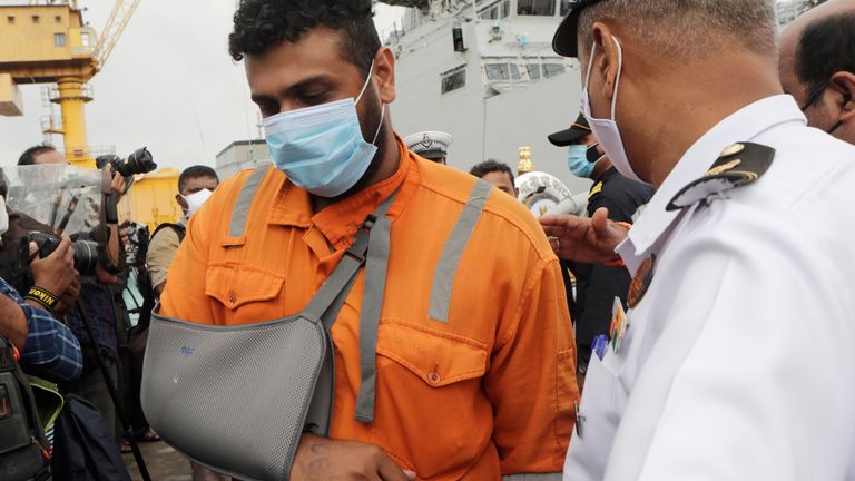 An injured man walks onto the docks at Mumbai after being rescued by the Indian navy from a barge that sank in the Arabian sea