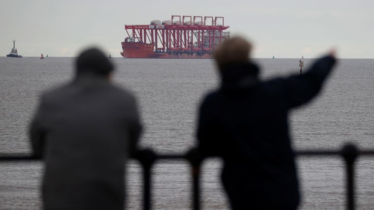 People watch as the Zhen Hua 36 heavy lift vessel enters the River Mersey with its cargo of gantry cranes for use at Peel Ports Group Liverpool container port at Crosby, Britain, March 4, 2021.