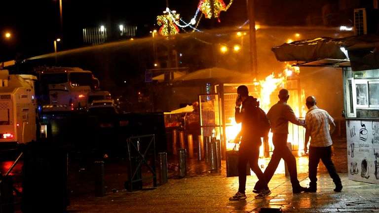 An Israeli police water cannon is deployed near the Damascus Gate to the Old City of Jerusalem as a fire burns during clashes between police and Palestinian protesters. Pic: AP