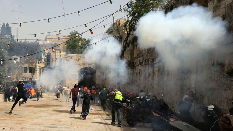 Palestinians run away as Israeli police fire a stun grenade