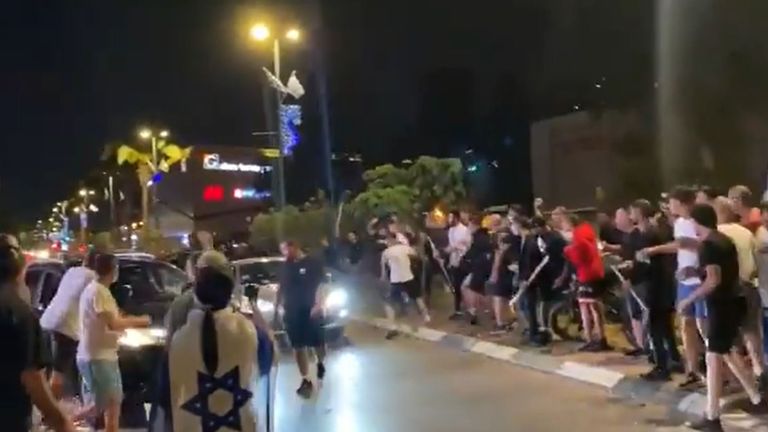 A crowd waving Israeli flags and carrying batons prepare to hit the passing car in Ramala. Pic: @bar_peleg