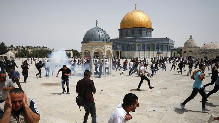 People run as the Israeli police fire tear gas and grenades outside the Al Aqsa Mosque