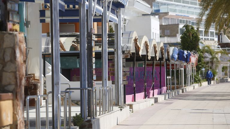 A man walks next to closed terrace bars in Magaluf beach sea promenade in the Spanish island of Mallorca, as many commerces remain closed in the Balearic Islands, amid the coronavirus disease (COVID-19) pandemic, Spain March 24, 2021. REUTERS/Enrique Calvo