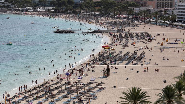 Tourists sunbathe and swim at the beach of Magaluf on the island of Mallorca, Spain, in 2017