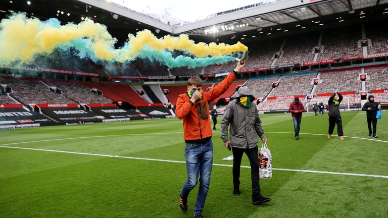 Soccer Football - Manchester United fans protest against their owners before the Manchester United v Liverpool Premier League match - Manchester, Britain - May 2, 2021 Manchester United fan with a flare on the pitch in protest against their owners before the match Action Images via REUTERS/Carl Recine
