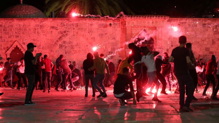 Palestinians react as Israeli police fire stun grenades during clashes at the compound that houses Al-Aqsa Mosque, known to Muslims as Noble Sanctuary and to Jews as Temple Mount