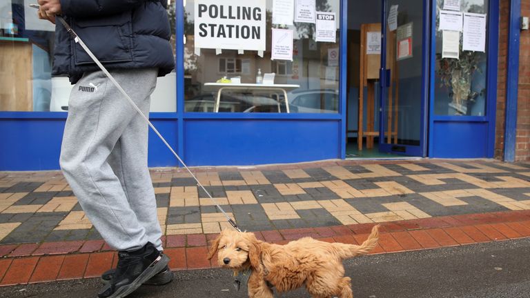 A man walks with a dog past a polling station during local elections in Oxford, Britain May 6, 2021. REUTERS/Peter Cziborra
