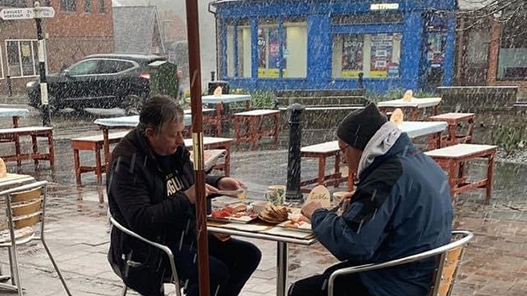 Two men eating their meal at Yangaz Bistro Grill in Cranleigh, Surrey at 0800 on Monday morning during wintry conditions. Pub-goers will need to wrap up warm on Monday, as chilly temperatures are forecast for the first day of outdoor hospitality reopenings in England. Picture date: Monday April 12, 2021.