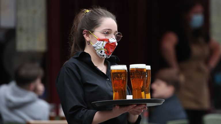A server carries a tray of drinks from a pub in the Grassmarket in Edinburgh, as beer gardens, non-essential shops, restaurants and cafes, along with swimming pools, libraries and museums in Scotland reopen today after lockdown restrictions have eased. Picture date: Monday April 26, 2021.
