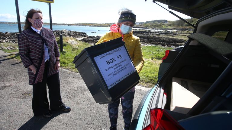Shona Barton, from the returning office team at Argyll and Bute Council hands over equipment to presiding officer Morven Beagan (R) for use at a polling station on the Isle of Gigha