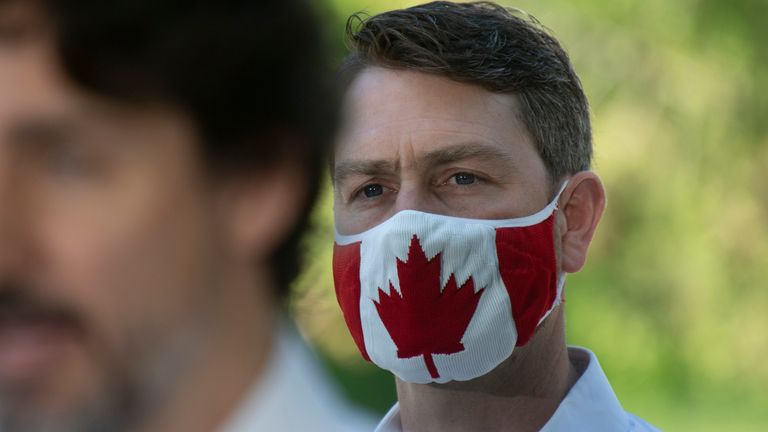 In this photo taken on June 19, 2020, Liberal Member of Parliament William Amos wears a Canadian flag mask as Prime Minister Justin Trudeau speaks during a news conference in Chelsea, Quebec